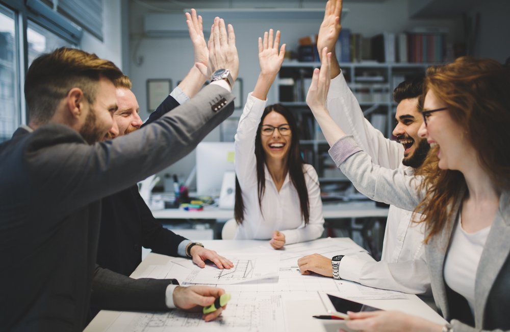 A group of people are giving each other a high five in an office.