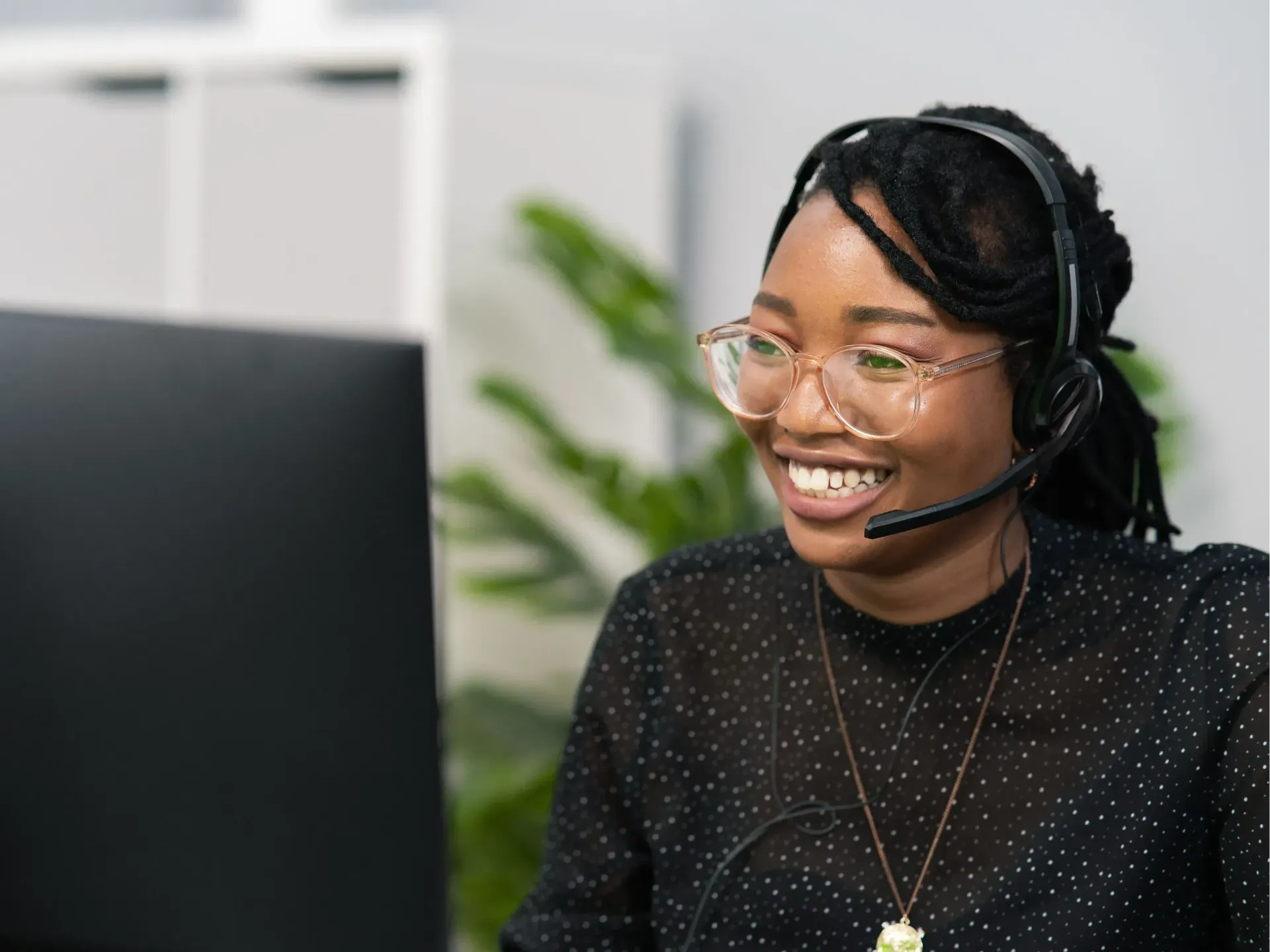 A woman wearing a headset is sitting in front of a computer.