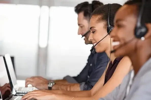 A group of people wearing headsets are working in a call center.