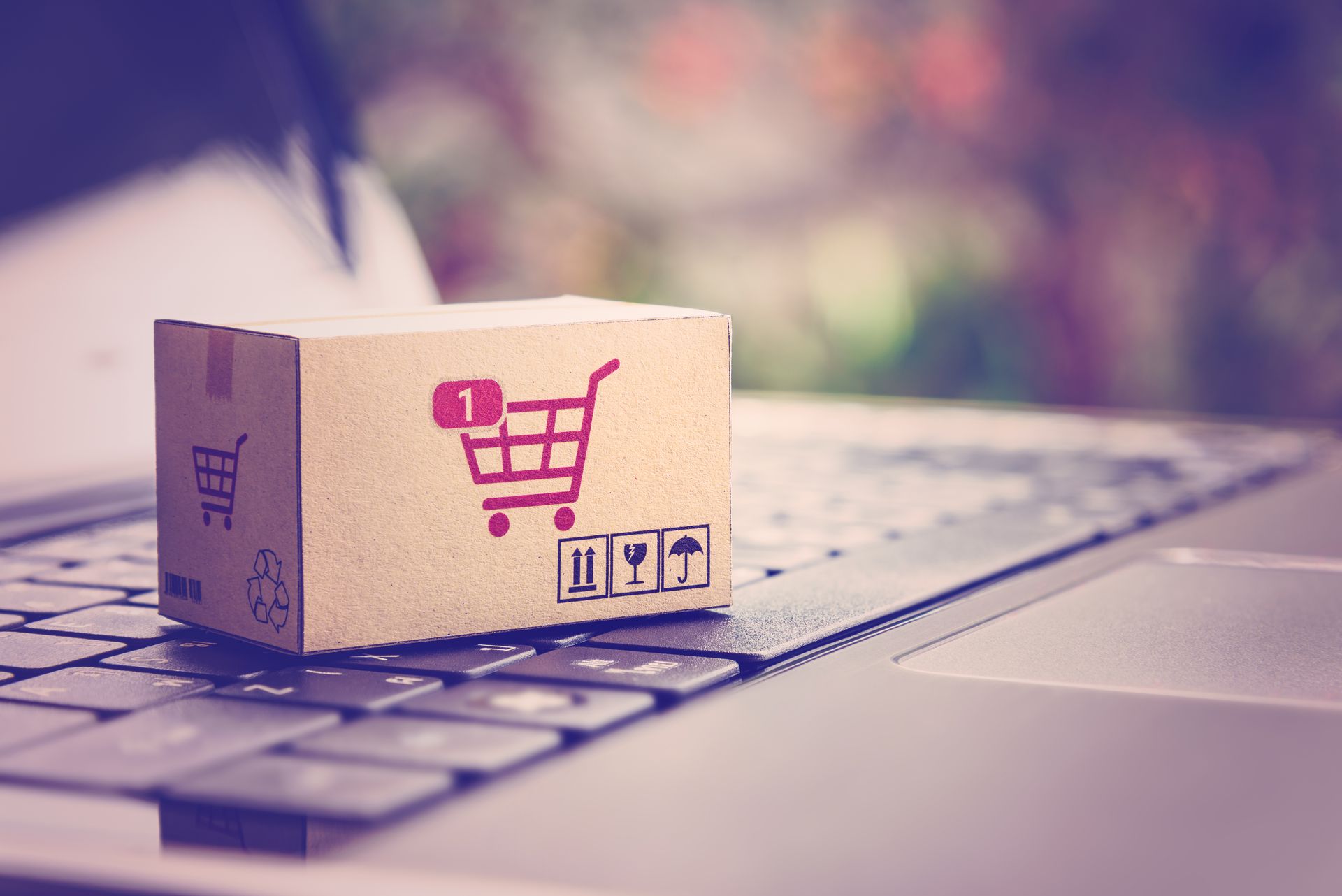 A cardboard box with a shopping cart on it is sitting on top of a laptop keyboard.