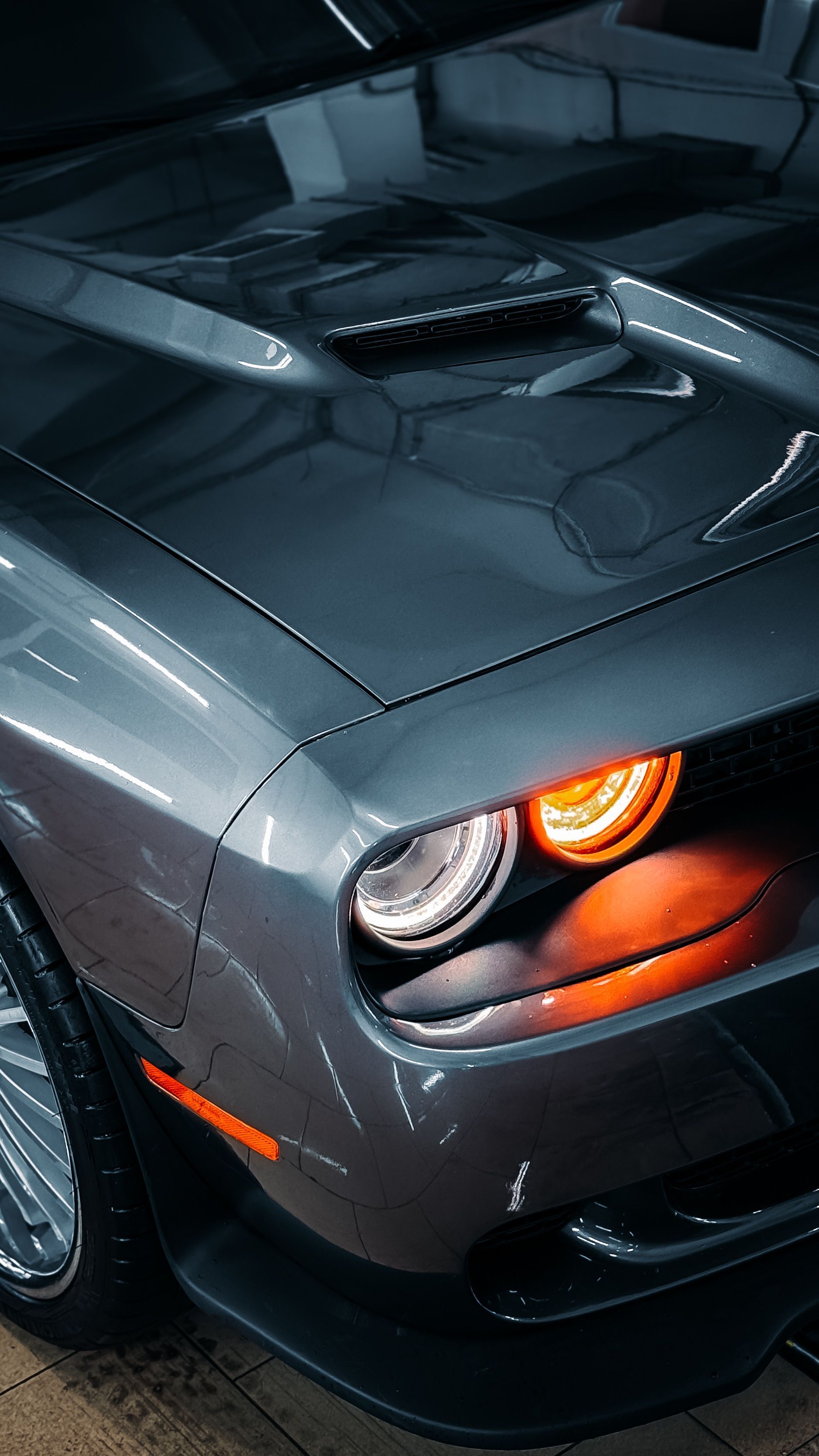 Person wiping a glossy black sports car with a white cloth in a dim garage