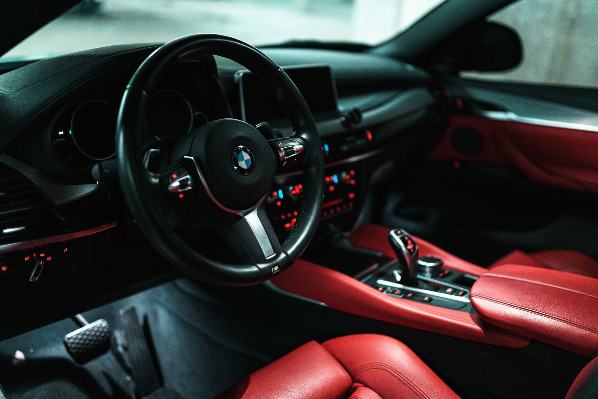 Red and black luxury car interior with steering wheel and dashboard