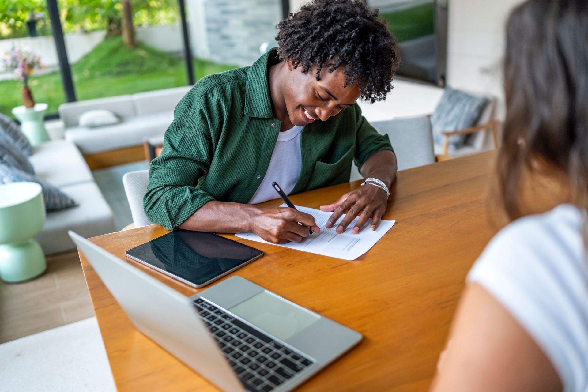 A woman is signing a document in an office in front of another woman. A woman is signing a document in an office in front of another woman.