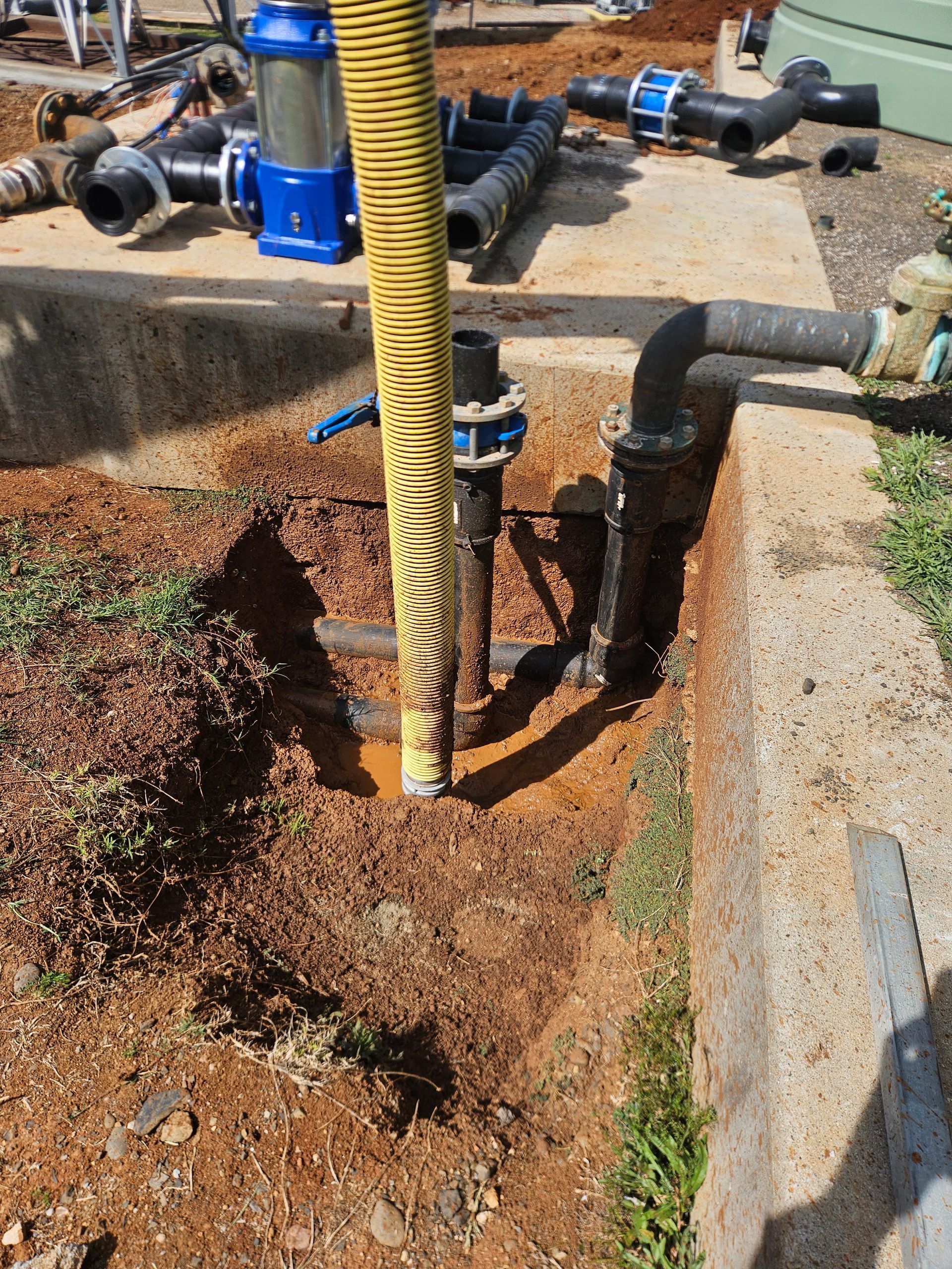 Vacuum truck parked near an industrial building with pipes.