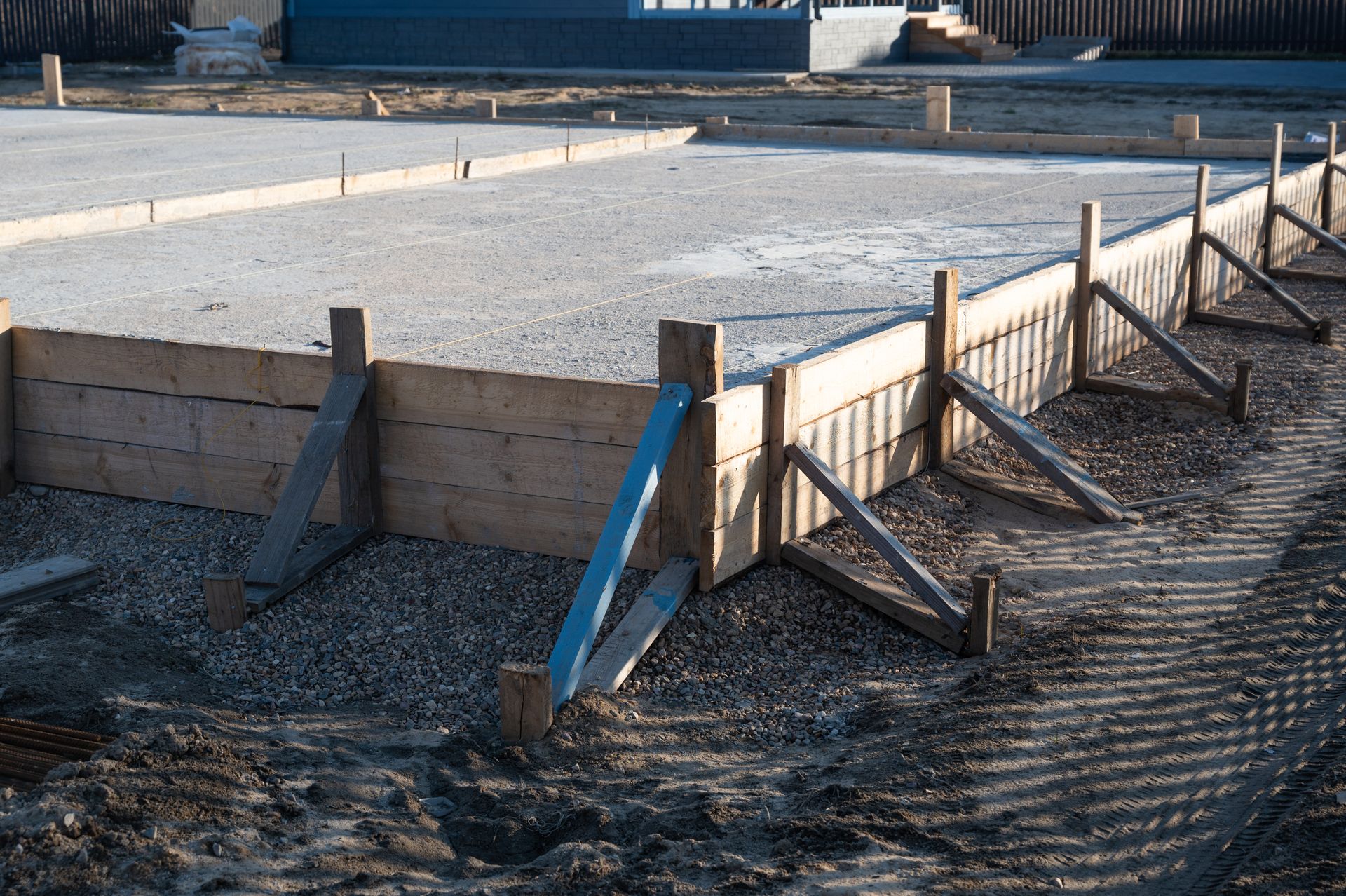 Ossature bois sur base en béton, sur un chantier de construction, soutenue par des entretoises en bois.
