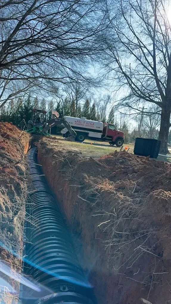 Utility truck and workers at the edge of a deep trench in a wooded area