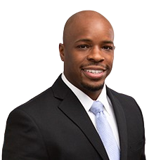 Man in black suit and light blue tie smiles at the camera.