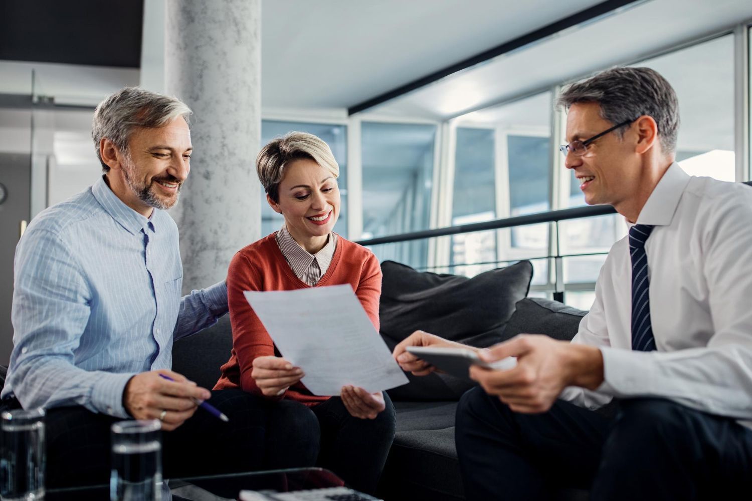 Three coworkers reviewing documents together in a modern office lounge