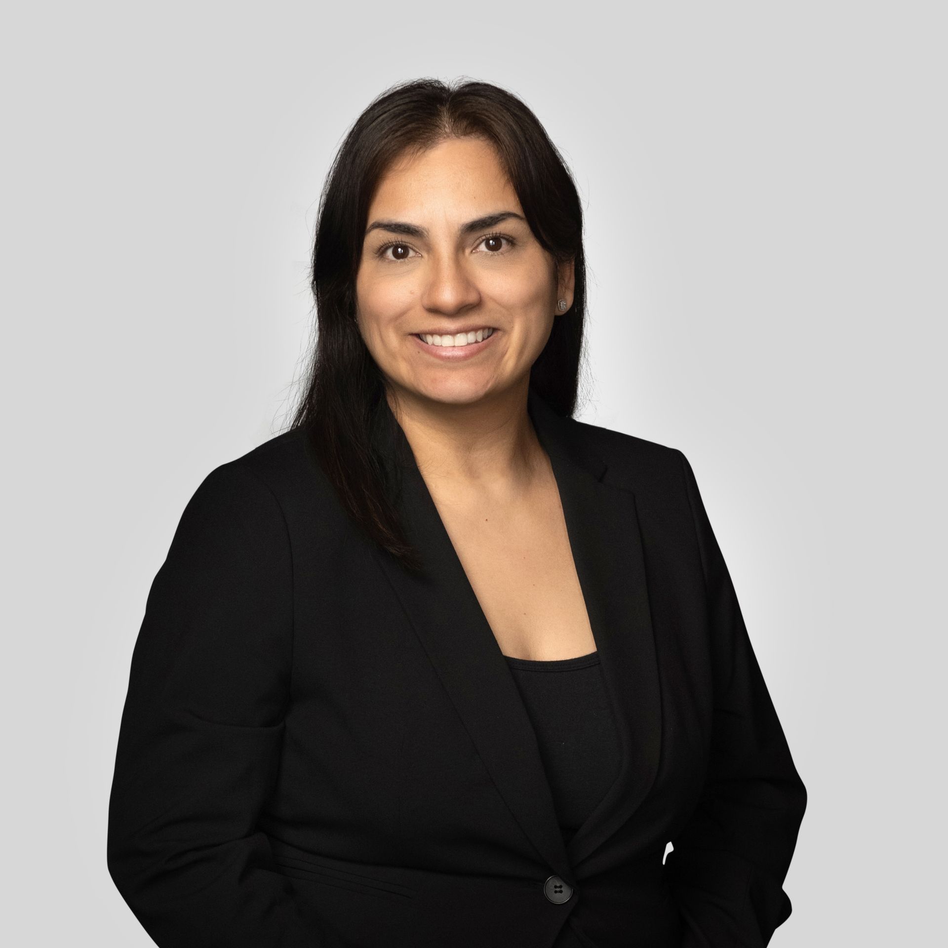 Professional headshot of a smiling person in a black blazer against a light gray background