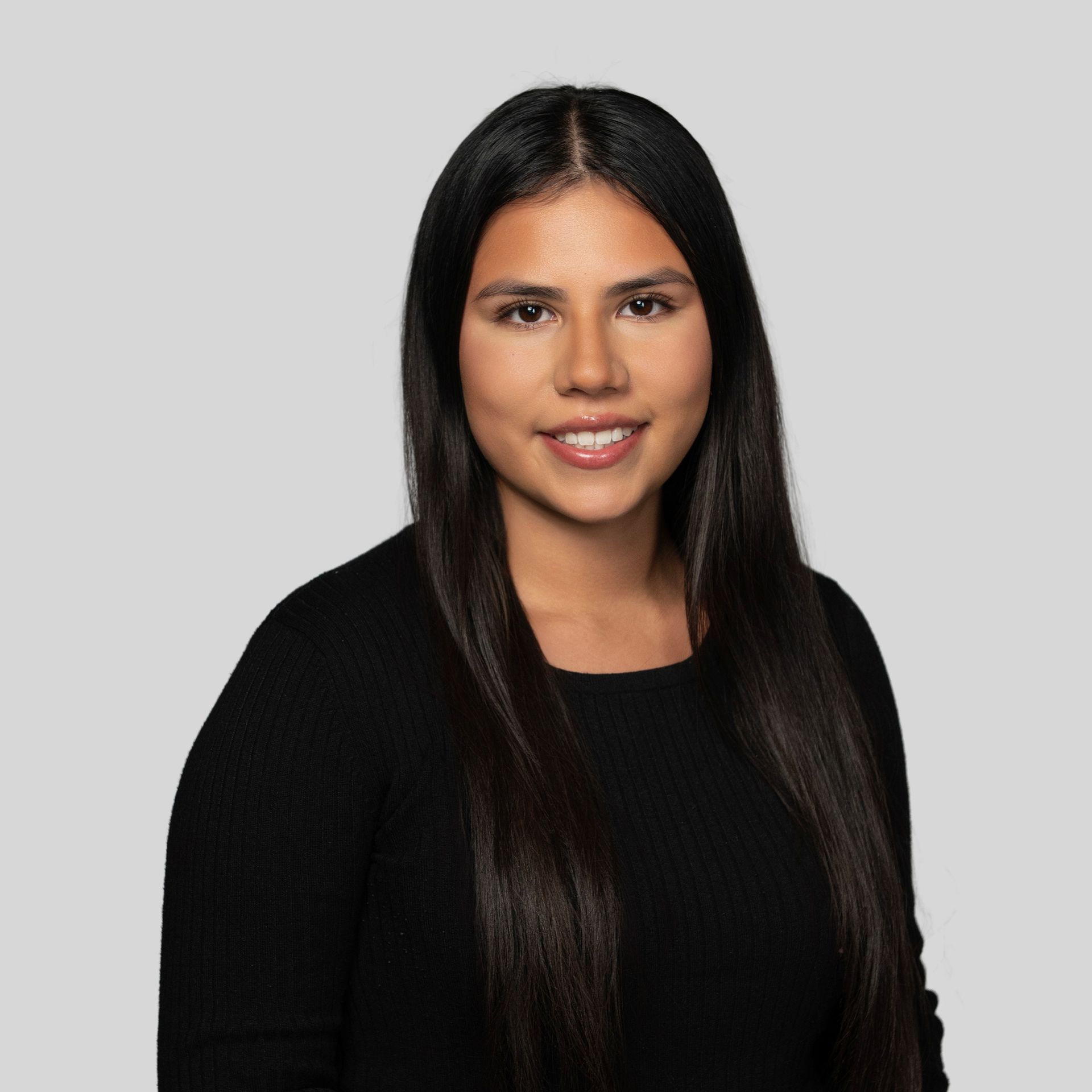 Portrait of a woman with long dark hair wearing a black top against a gray background