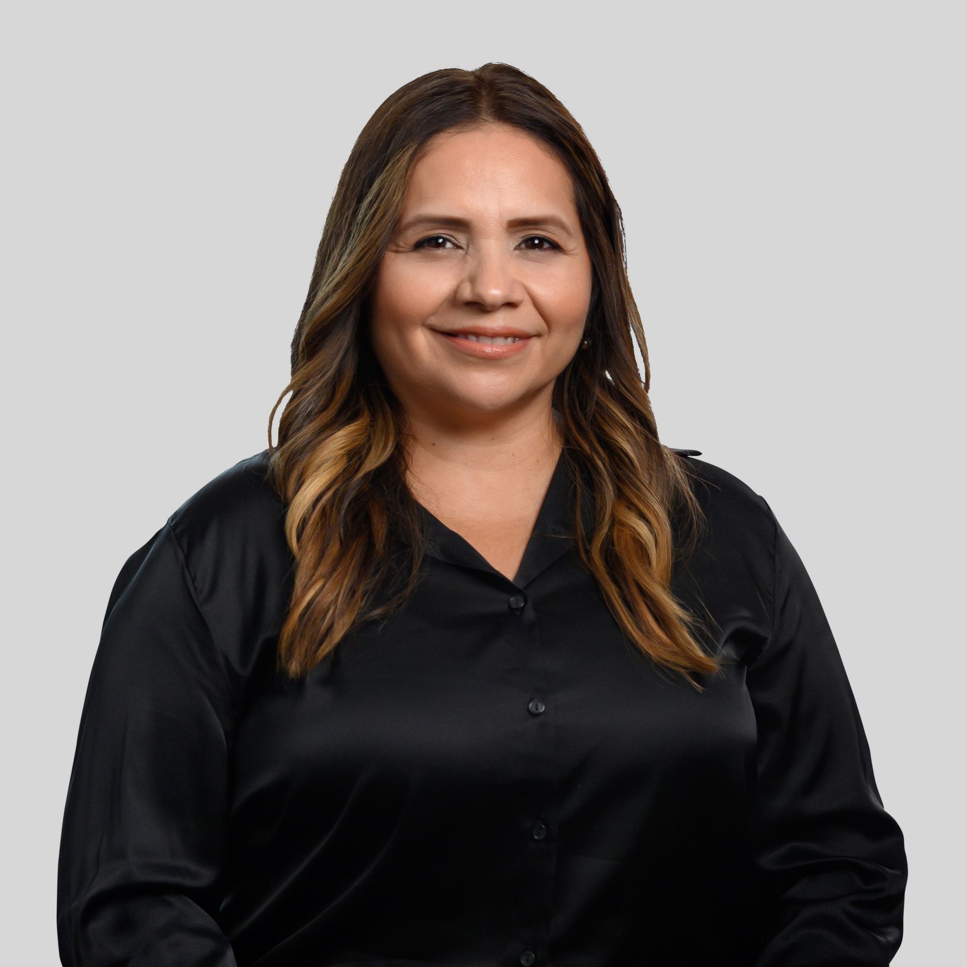 Portrait of a smiling woman in a black blouse against a plain gray background