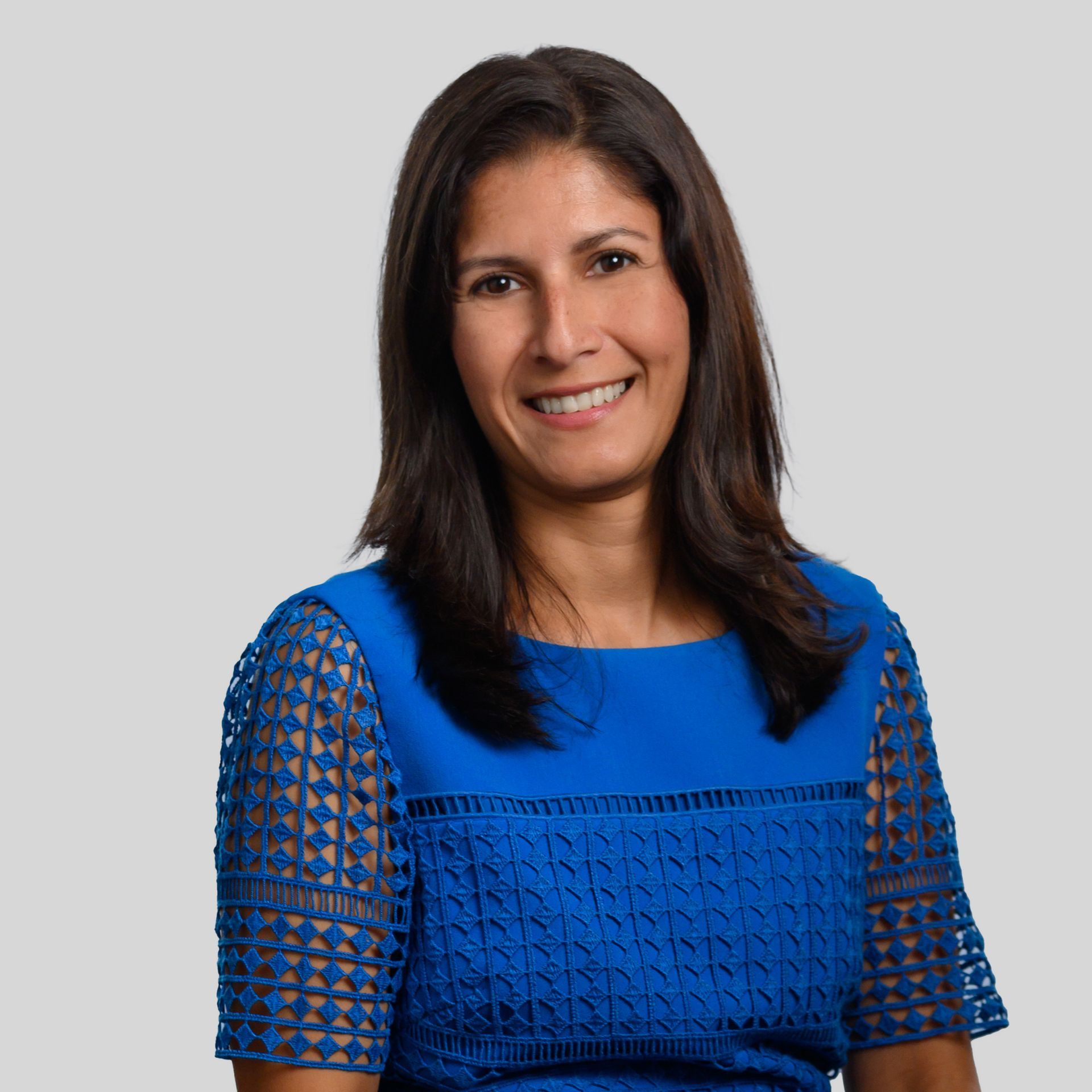 Portrait of a smiling woman in a blue top against a light gray background