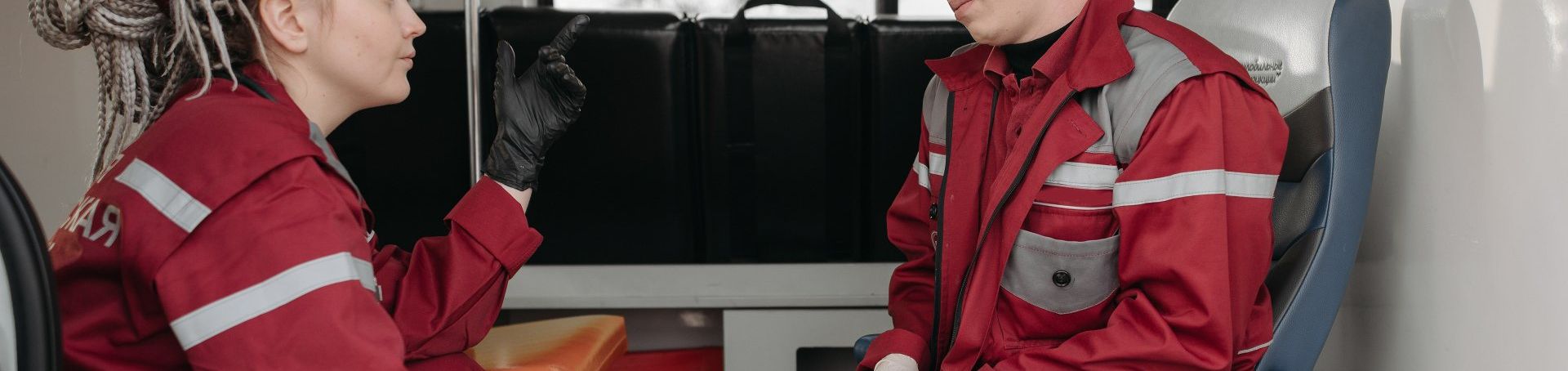 Two people in red jackets sitting across from each other in a train compartment