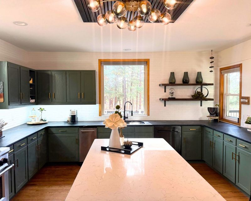 Modern kitchen with dark cabinets, white island, and large windows with natural light