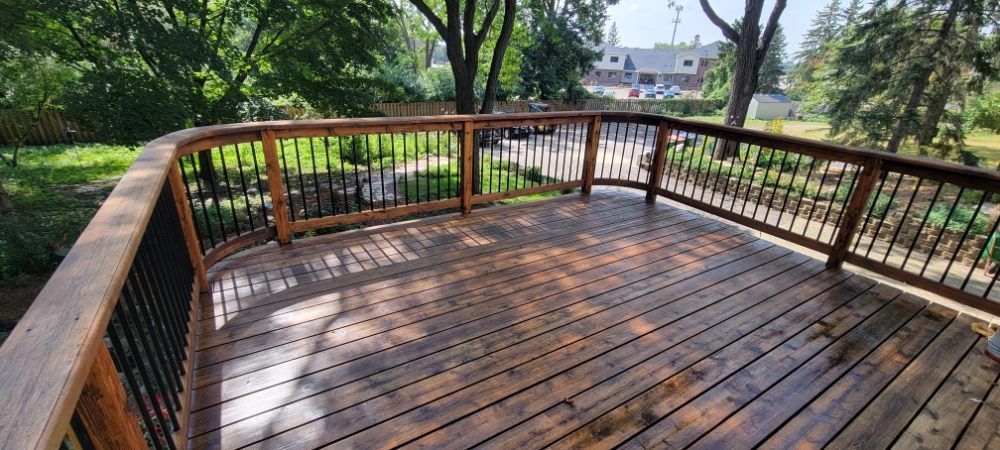Wooden deck overlooking a green park, with railings and trees in the background.
