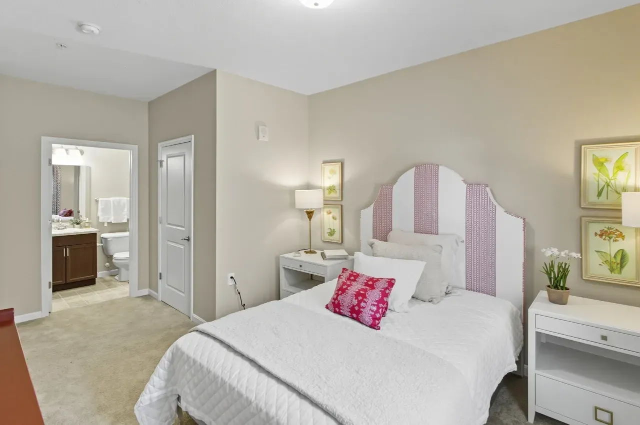Cozy bedroom with a queen-size bed, pink and white striped headboard, and a view into the bathroom.