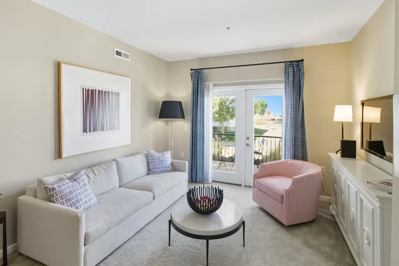 Cozy living room with a white sofa, pink armchair, coffee table, and patio access.