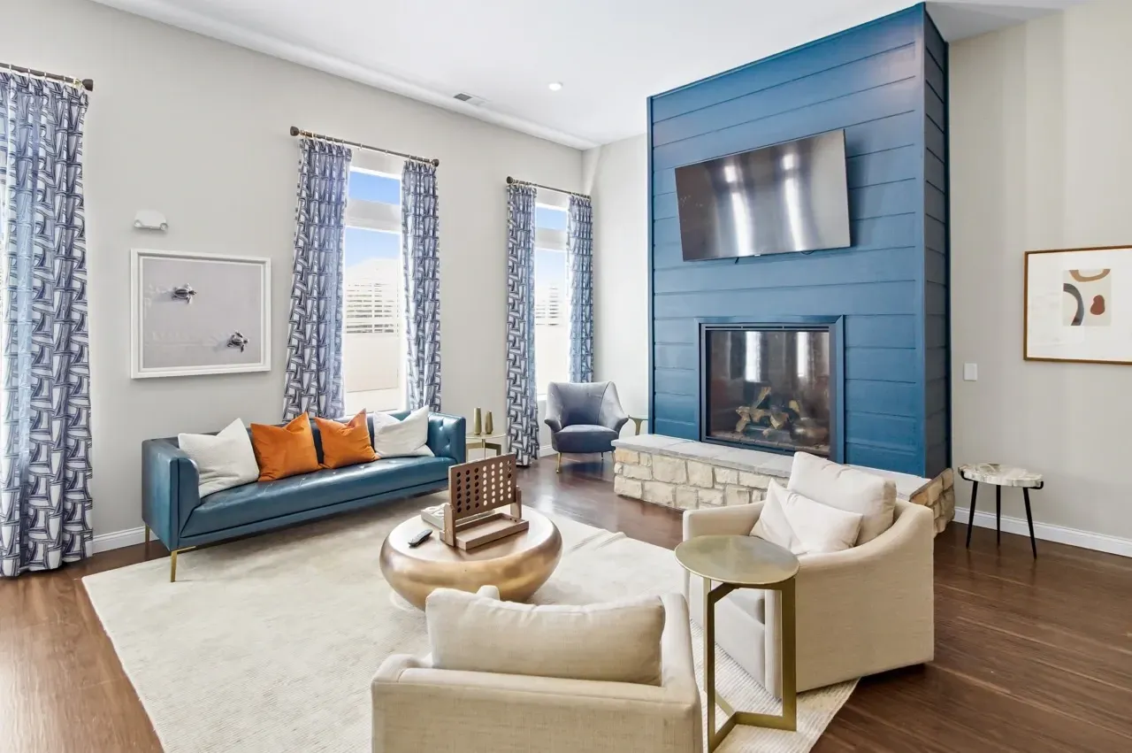 Modern living room with blue sofa, fireplace and large windows.