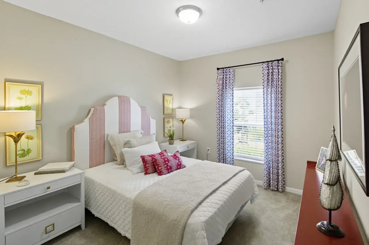 A bedroom with a queen-size bed, nightstand, and window.
