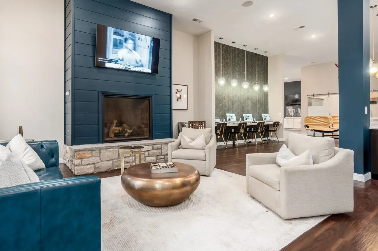 Cozy community lounge area with a fireplace, comfortable seating, and a business center with computers.