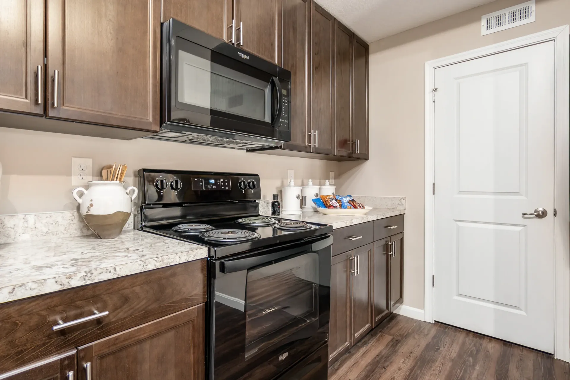 Modern kitchen with dark wood cabinets, granite countertops, and stainless steel appliances.