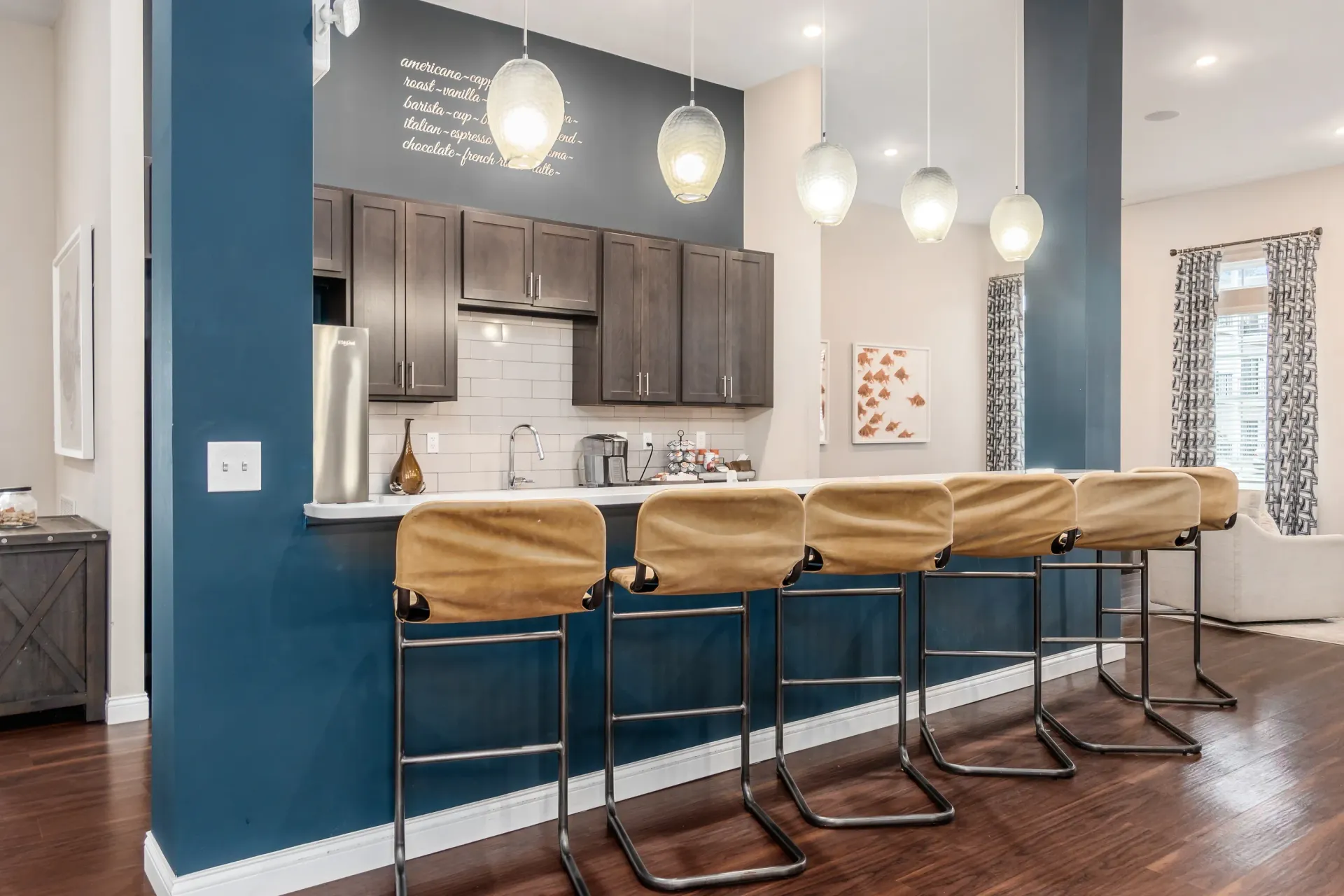 Community coffee bar with dark wood cabinets, white subway tile backsplash, and pendant lighting.