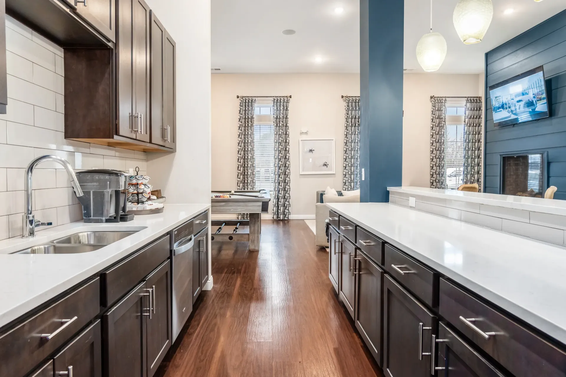 Gourmet kitchen with dark wood cabinets, stainless steel appliances, and a pool table in the background.