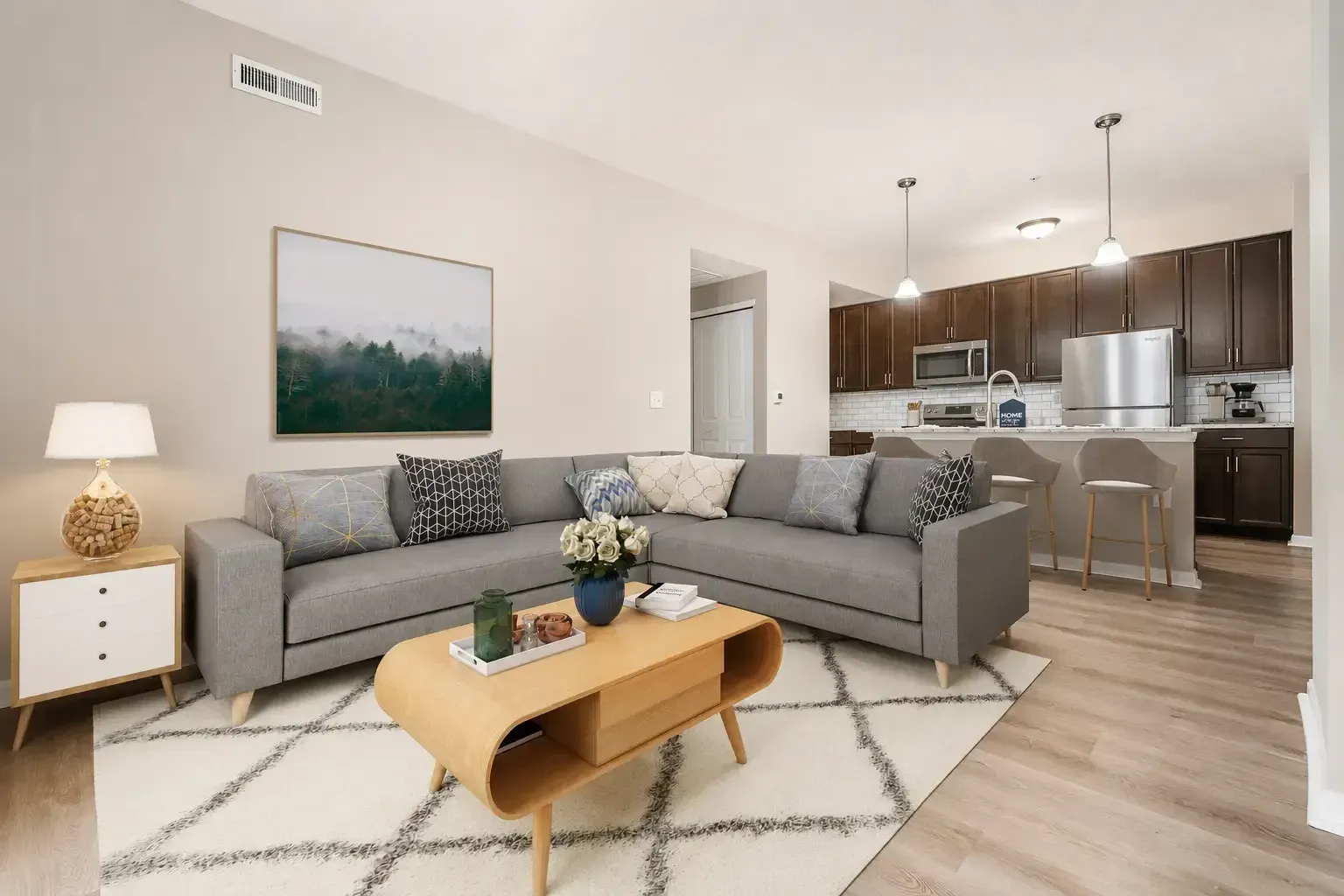 Modern living room with gray sectional, coffee table, and open kitchen in the background