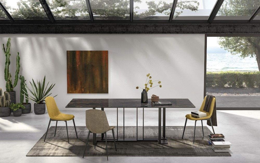 Sala da pranzo con tavolo, sedie, opere d'arte, piante e ampie finestre.