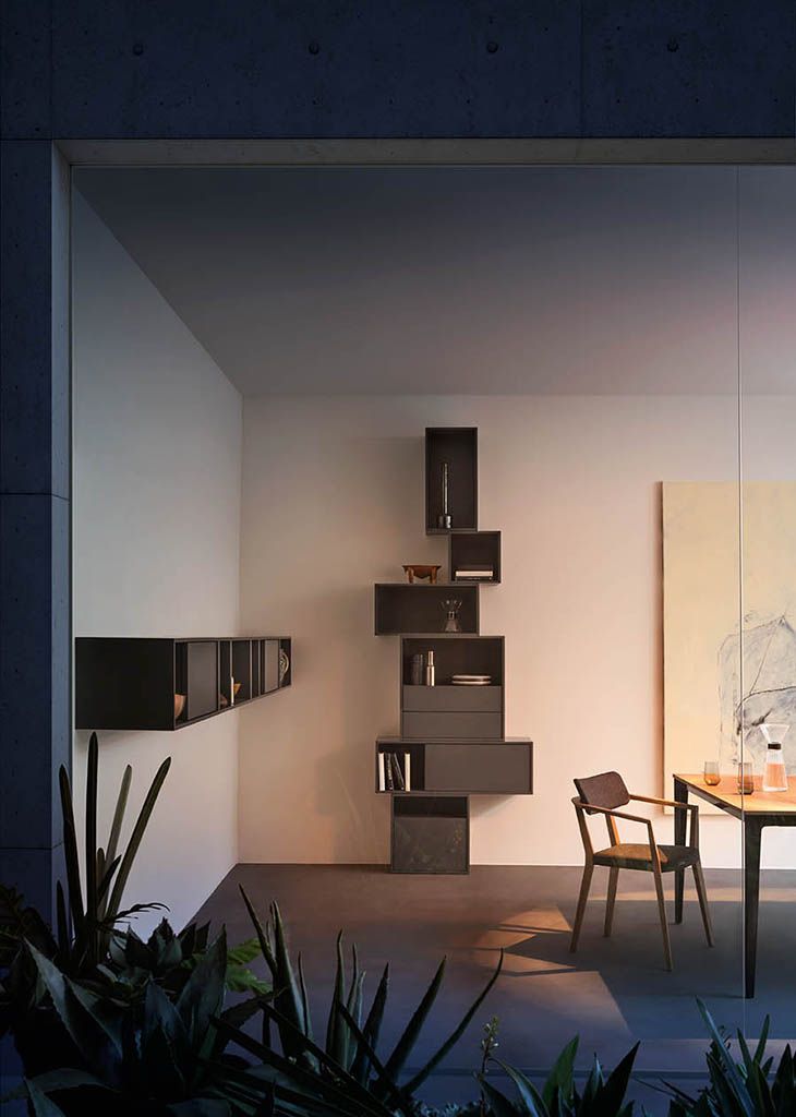 Interno moderno con mensole sospese scure su pareti bianche, tavolo da pranzo, sedia e opere d'arte.