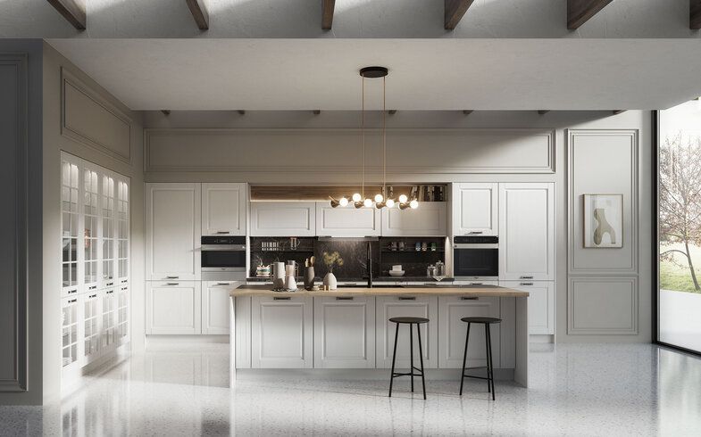Moderna cucina bianca con isola, dettagli neri, due forni, lampade a sospensione e ampia finestra.