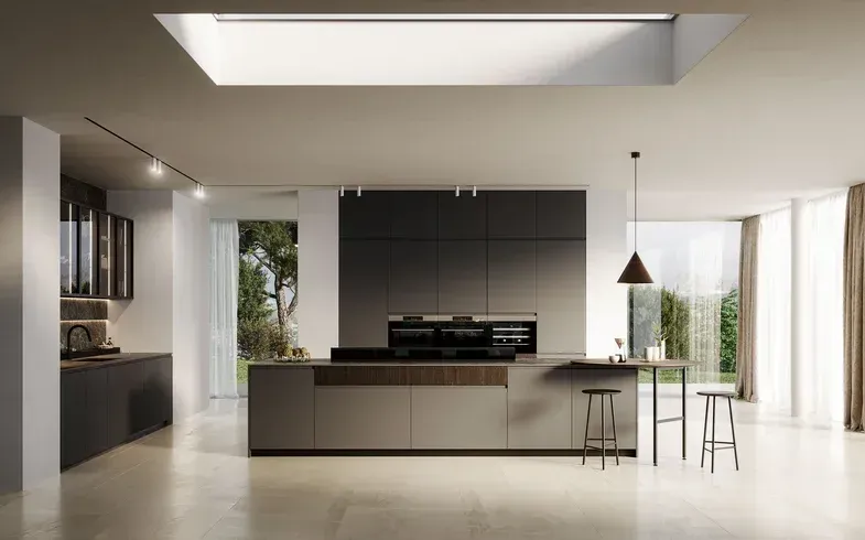 Cucina moderna con isola centrale, mobili scuri, pavimento chiaro, lucernario e vista sull'esterno.