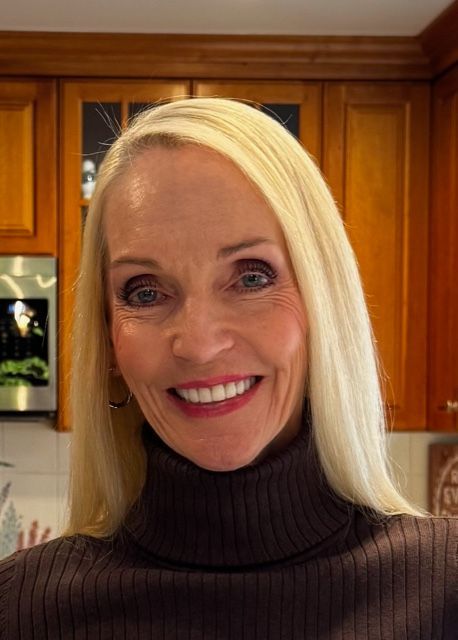 Woman with blonde hair wearing a brown turtleneck, smiling in a kitchen. Meet Drue! A licensed LCSW with years of experience.