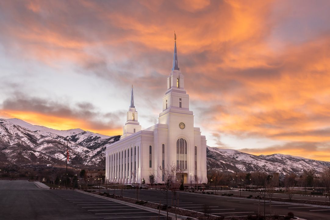 White temple in Layton with two spires against colorful sunset, mountains in background.