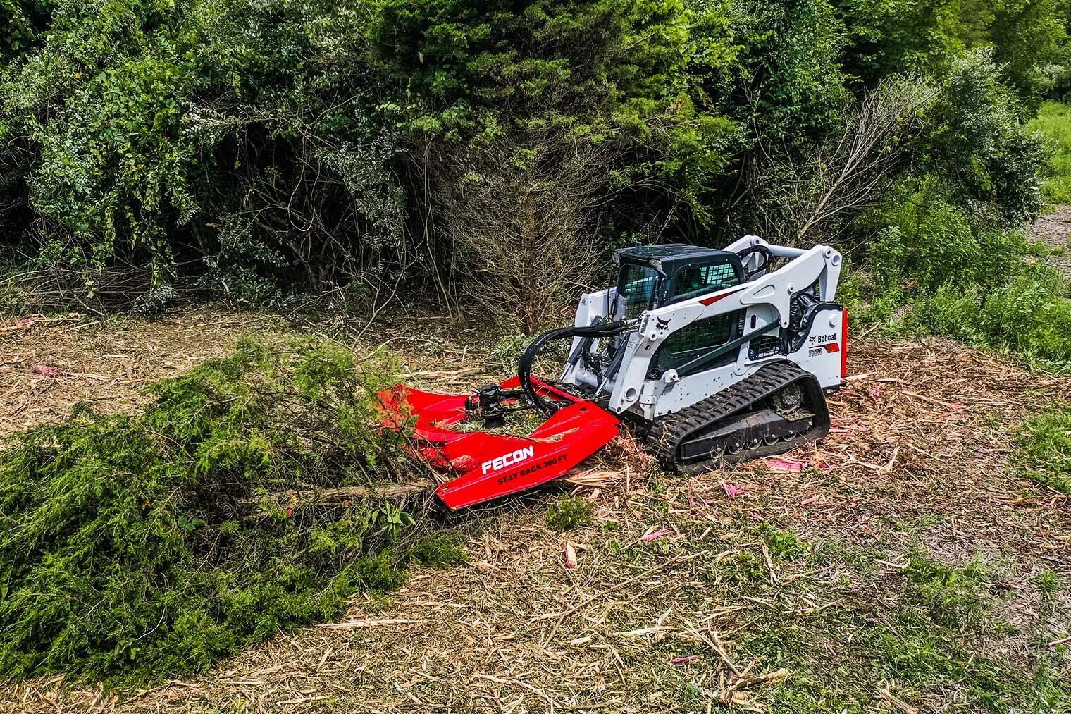 A bulldozer is cutting down trees in a field.