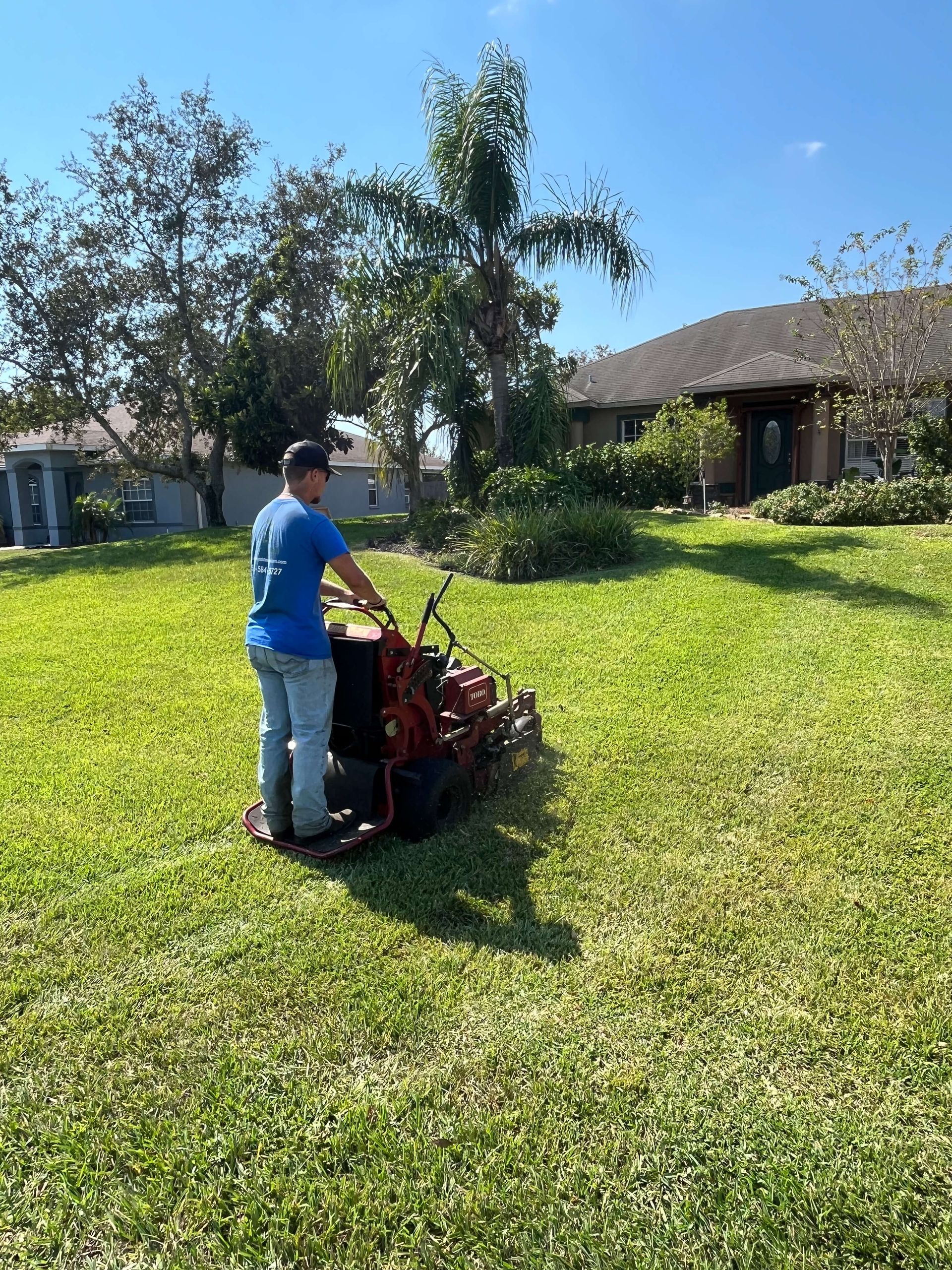 A man is mowing a lush green lawn with a lawn mower.