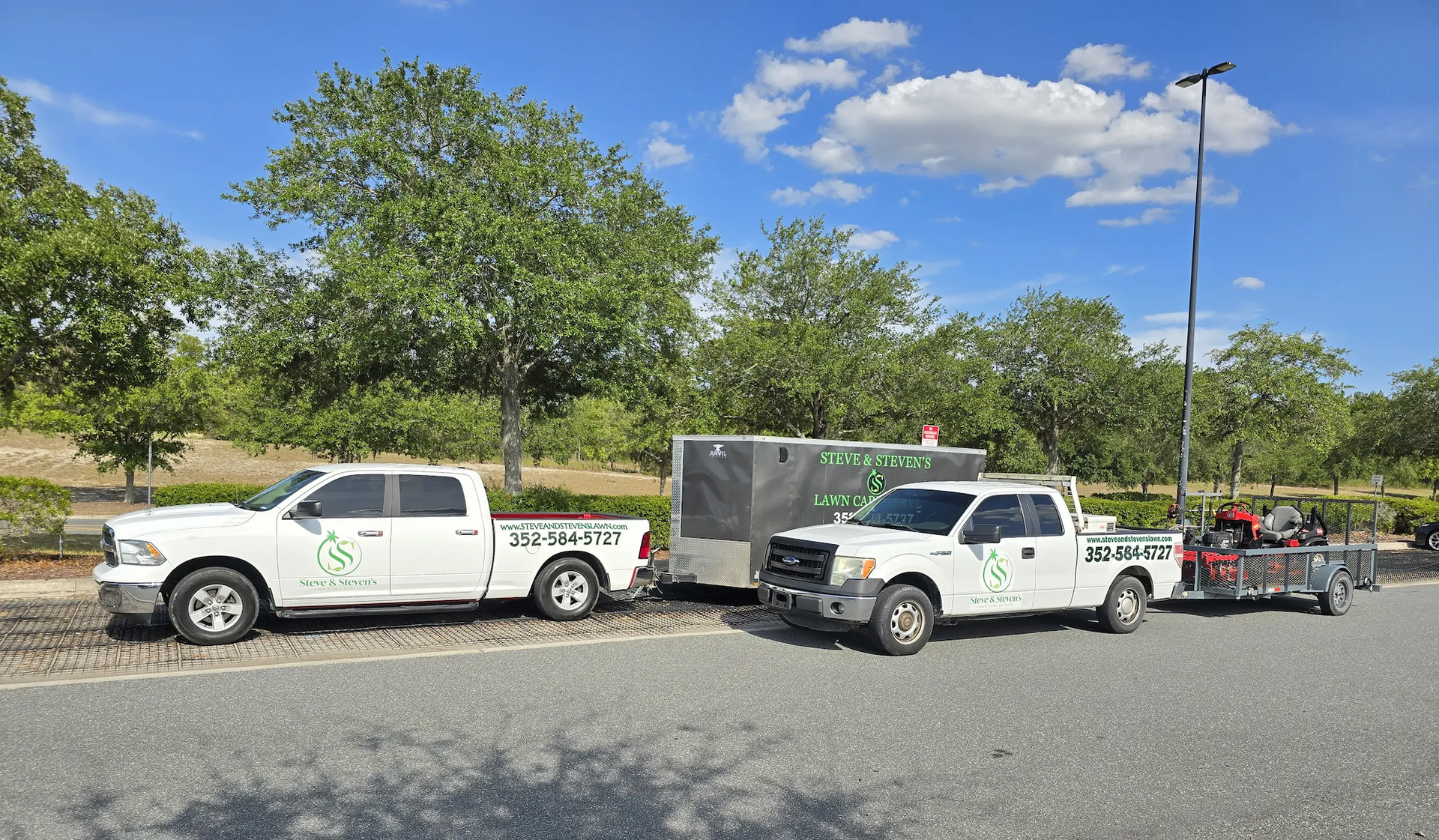 Two white trucks are parked next to each other on the side of the road.
