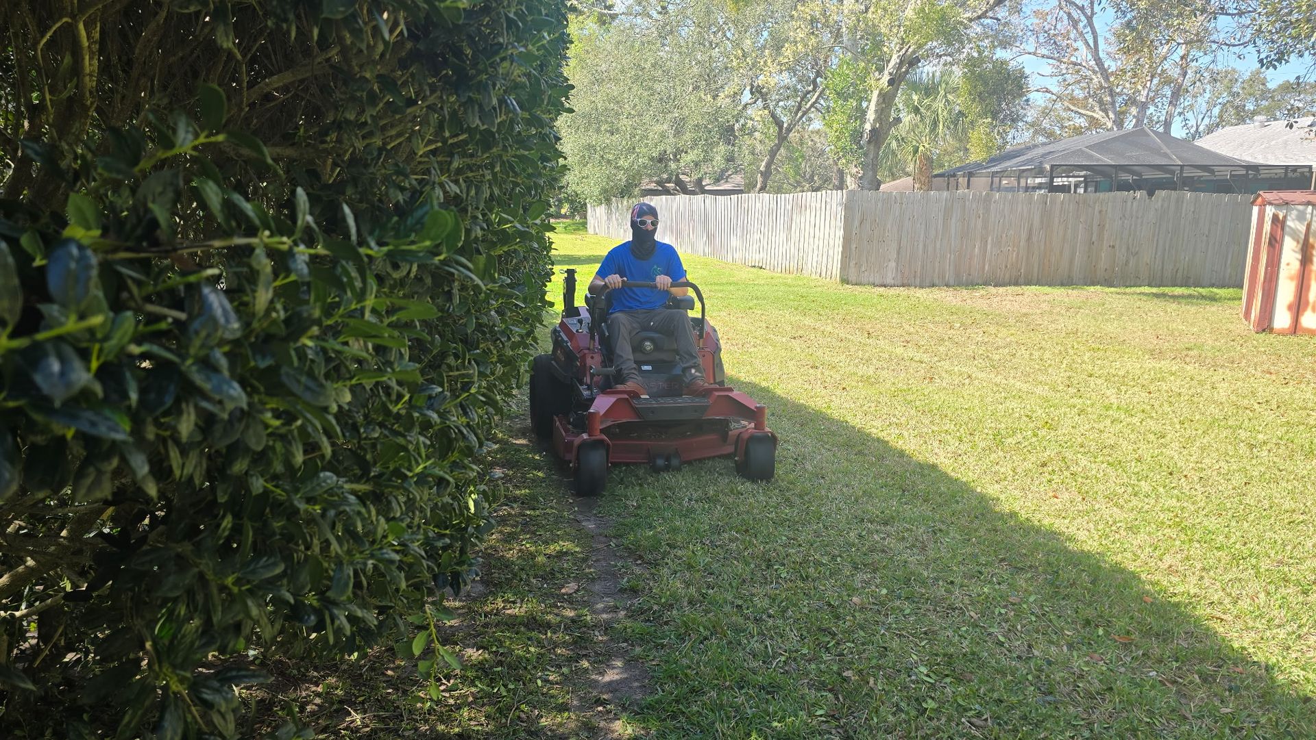 A man is riding a lawn mower through a lush green yard.