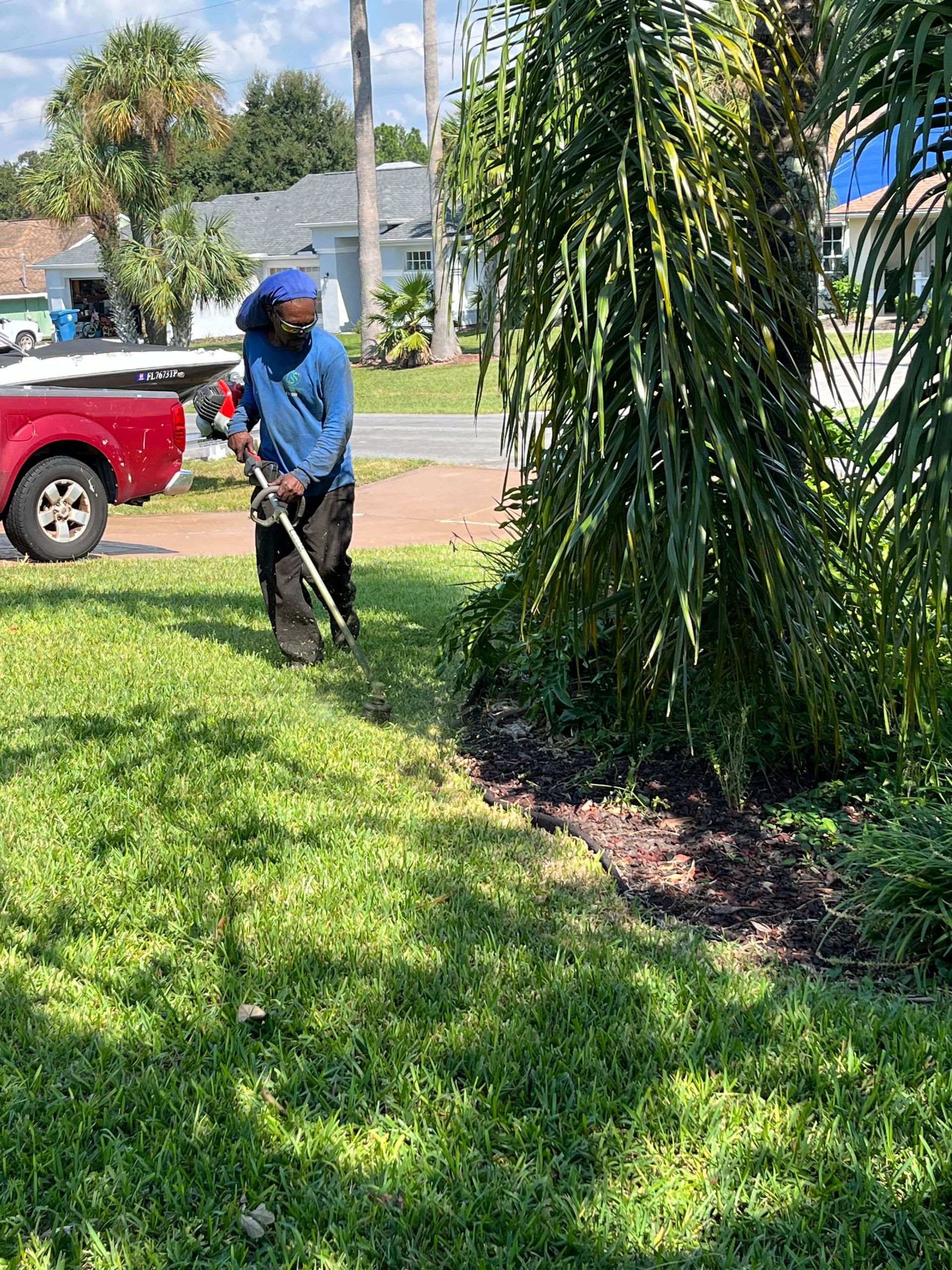 A man is mowing the grass in front of a red truck.