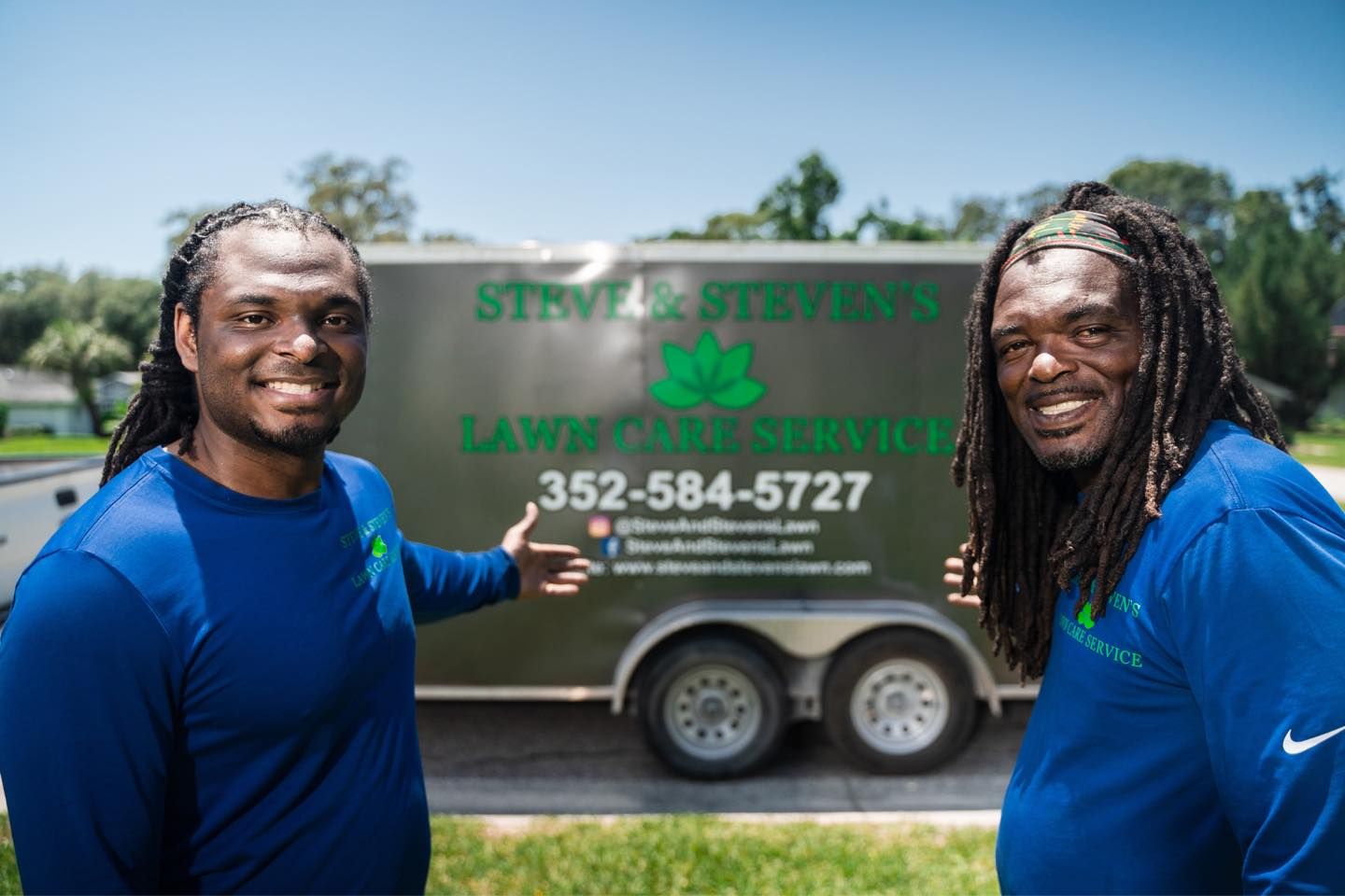 Two men are standing next to each other in front of a trailer.