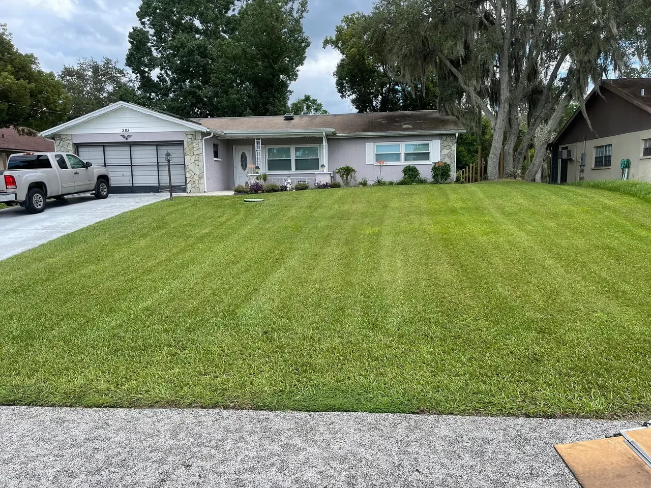 A truck is parked in front of a house with a lush green lawn.