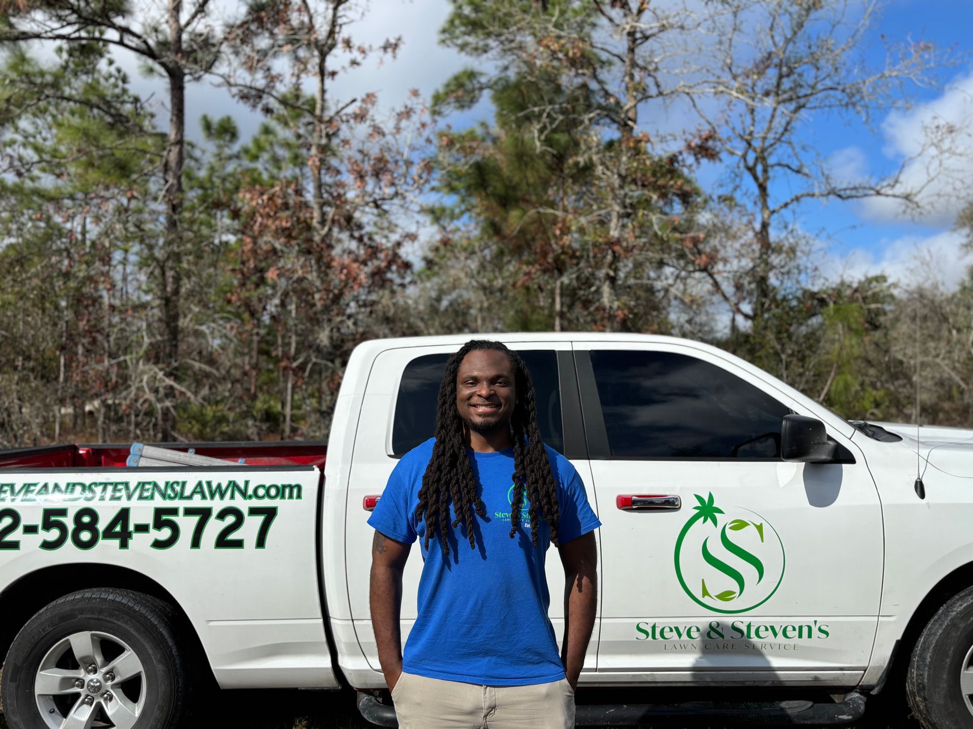 A man in a blue shirt is standing in front of a white truck.