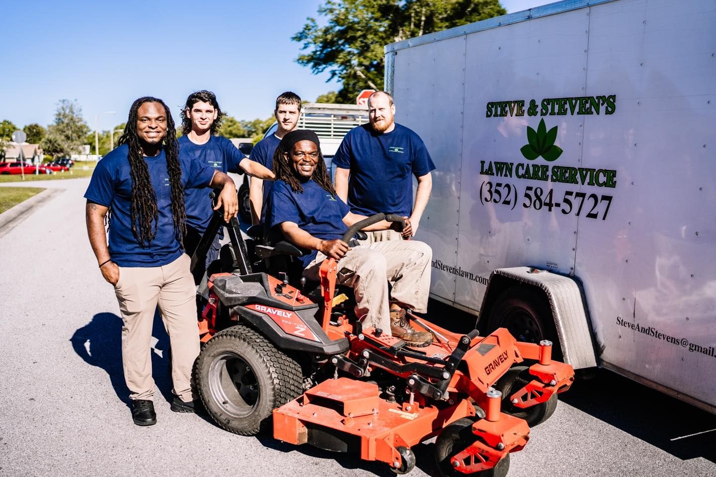 A group of people standing next to a lawn mower.
