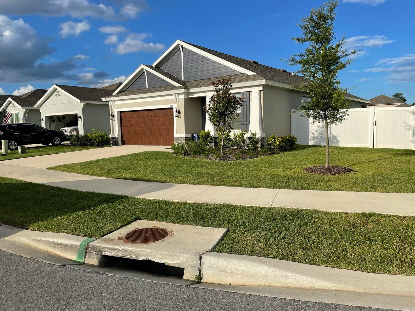 A white house with a wooden garage door is sitting on top of a lush green lawn.