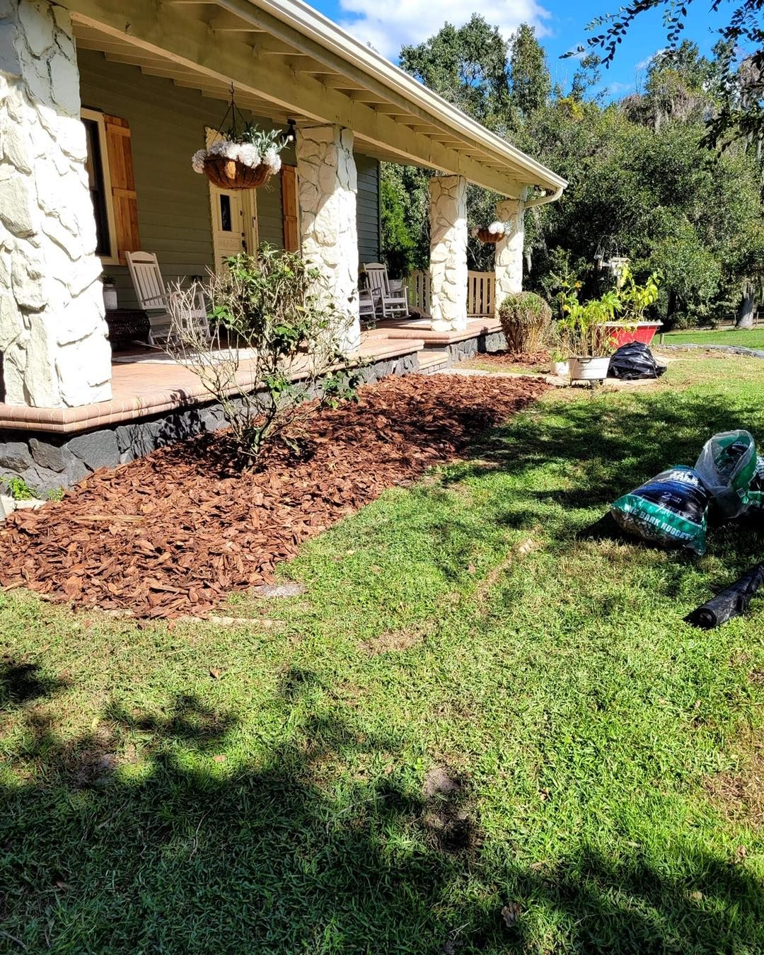A house with a porch and a lot of mulch in front of it.