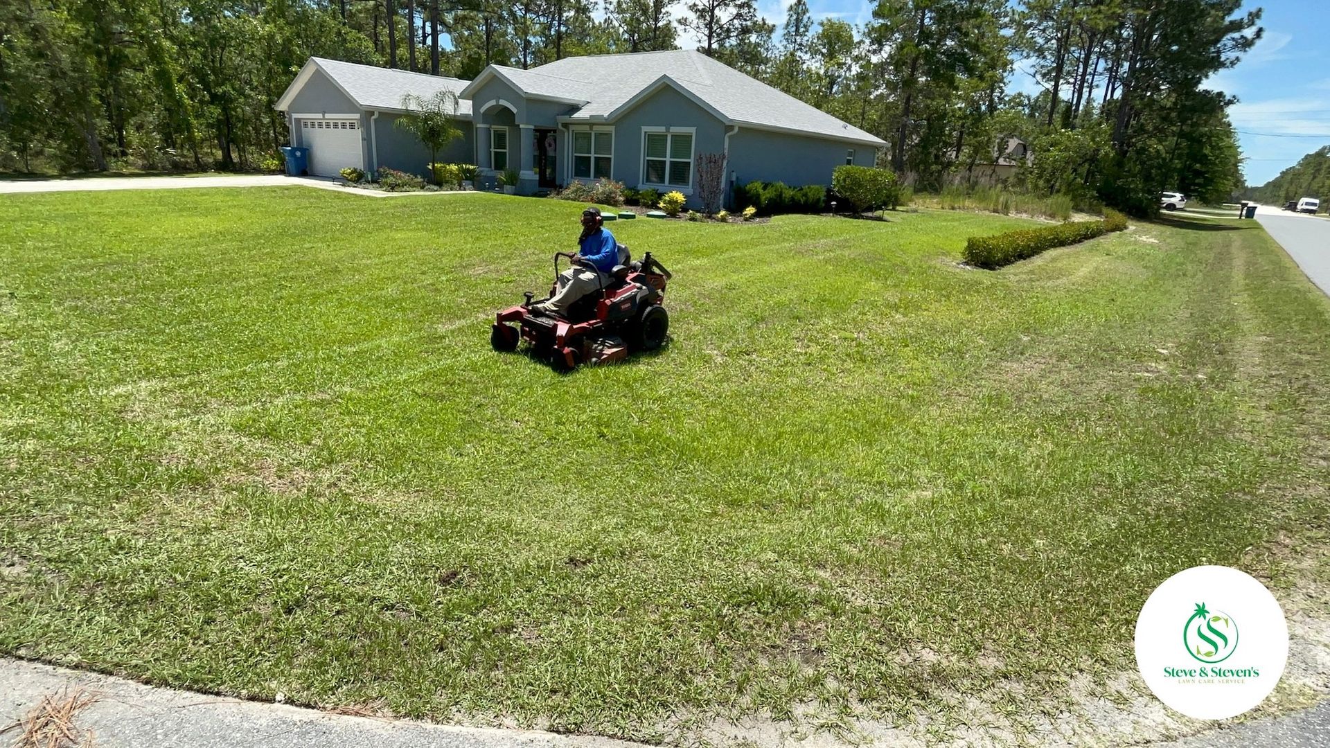 A man is riding a lawn mower in front of a house.