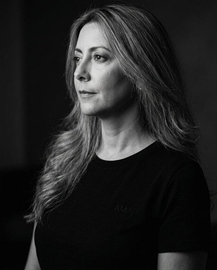Portrait en noir et blanc d'une femme aux longs cheveux, regardant vers la gauche sur un fond sombre.
