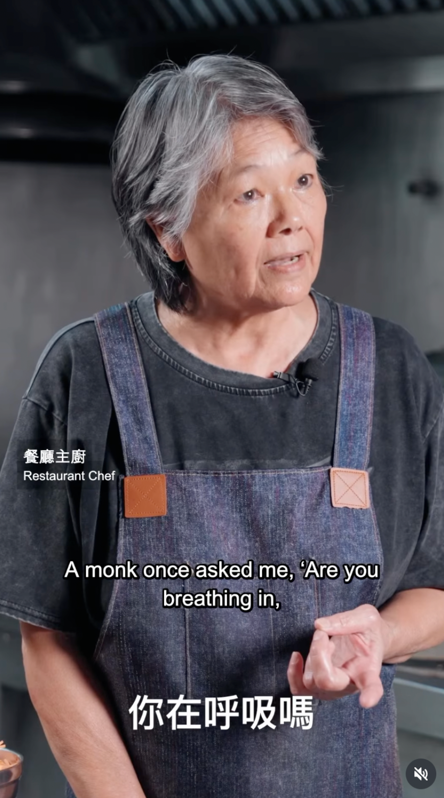 正念動中禪真實學員故事,一位灰白短髮的餐廳主廚身穿深色圍裙,在廚房接受訪談,分享法師關於呼氣與吸氣的提問,以及接觸十五個手部動作的經歷。