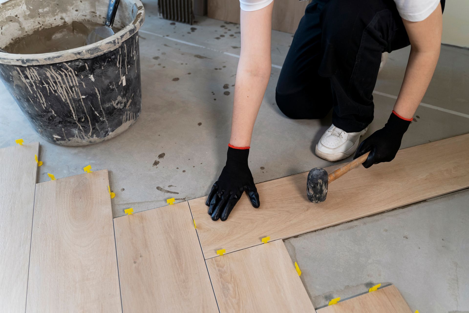 A man is kneeling down to install a wooden floor.