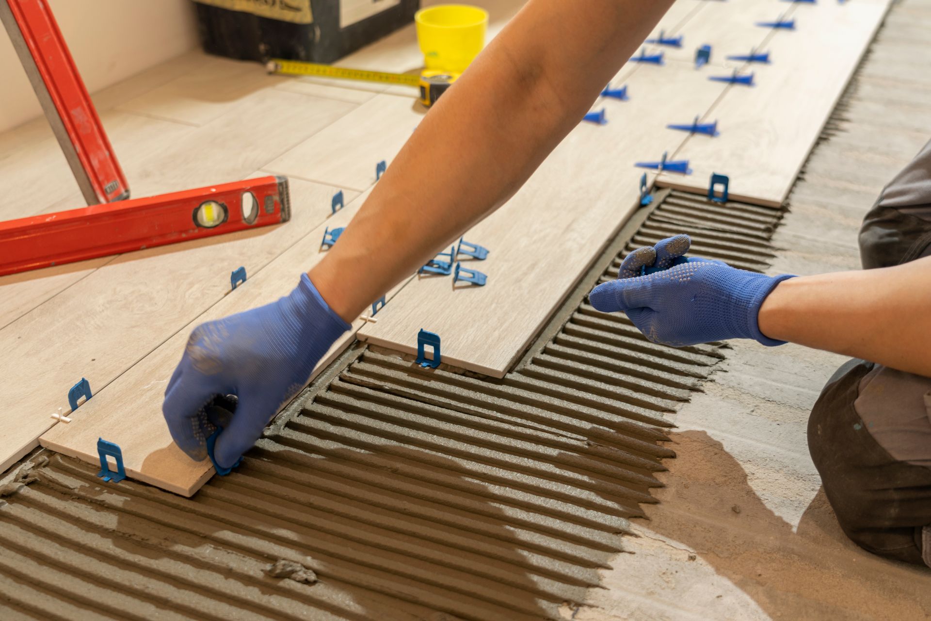 A man is kneeling down to install a wooden floor.
